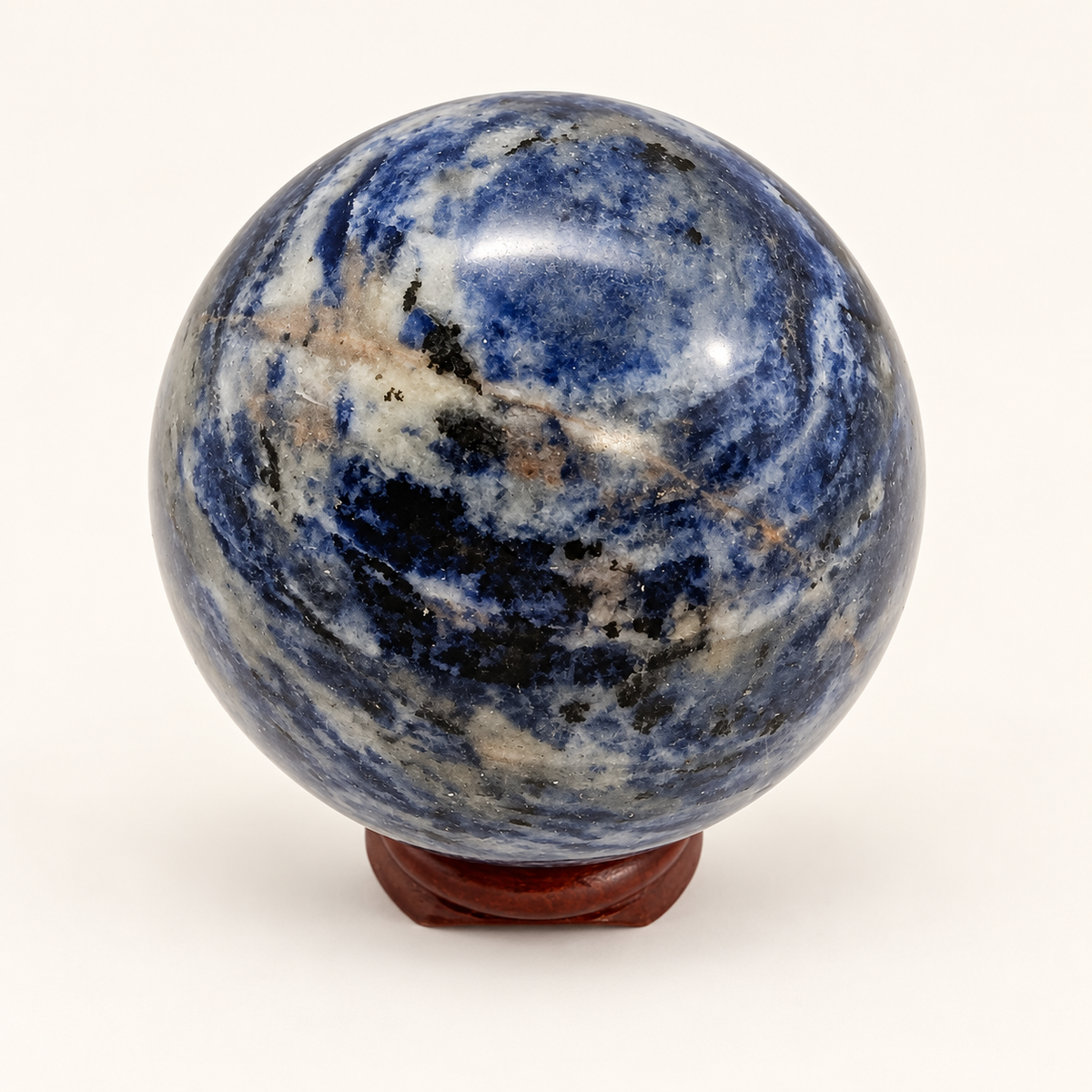 5 cm Blue Sodalite sphere with blue, grey and cream patterning on a wooden display stand