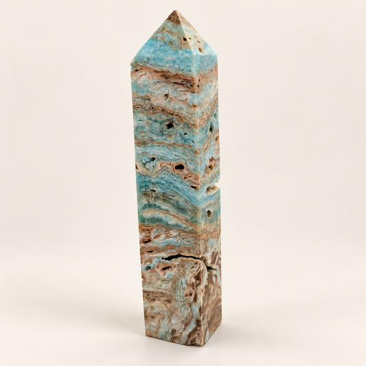 18 cm Caribbean Calcite tower with blue-green, cream and brown bands and visible cavities against an ivory background