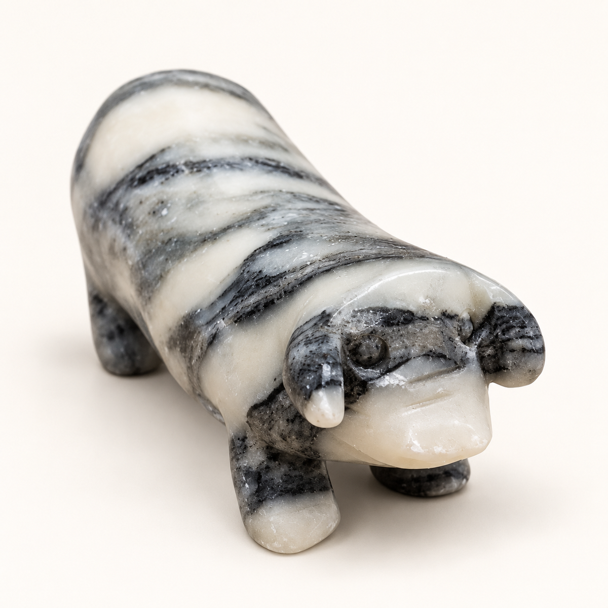 Grey Sunstone pig carving with white and charcoal banding on an ivory background