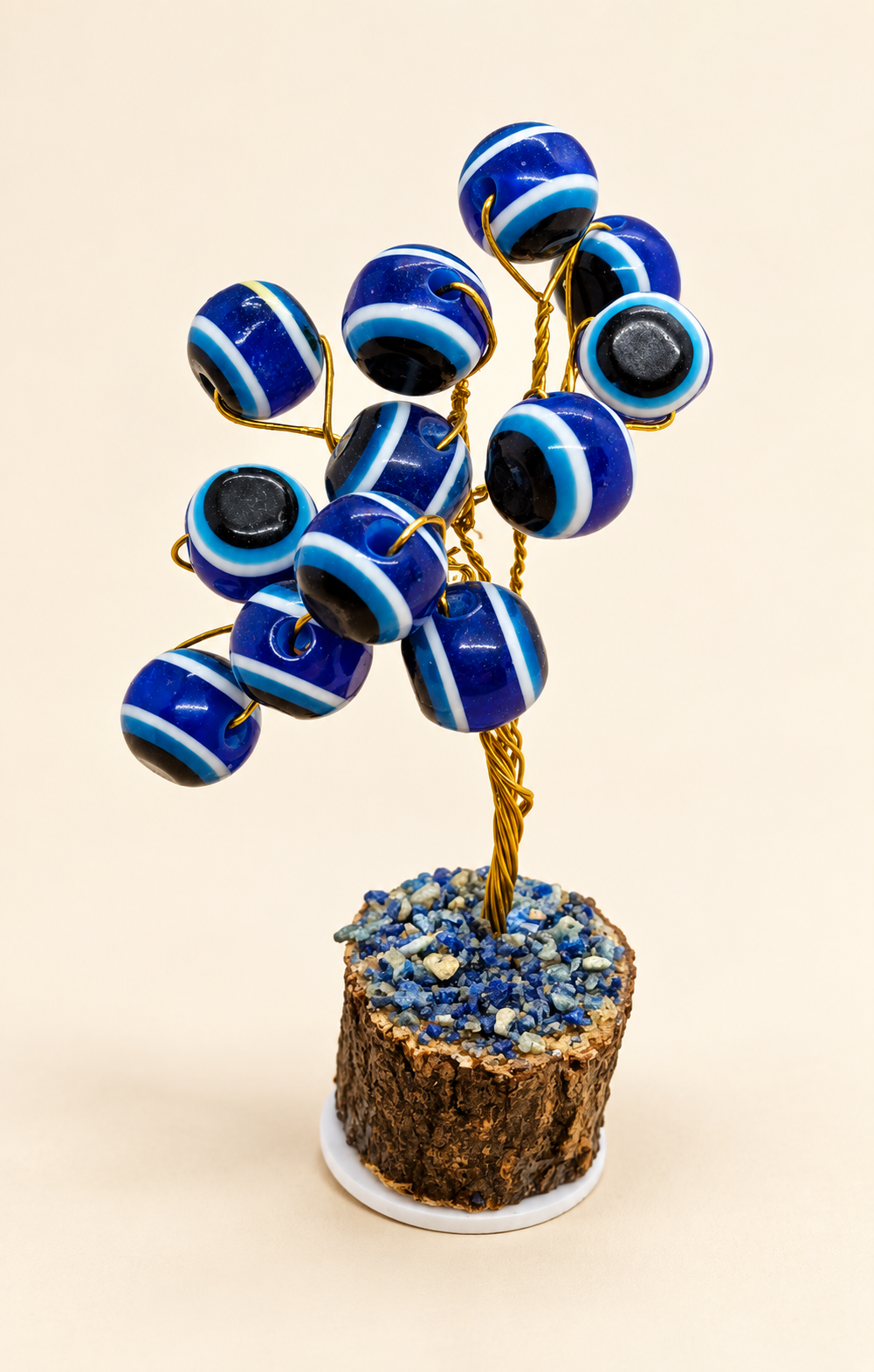 Small handmade blue evil eye tree on a cream background