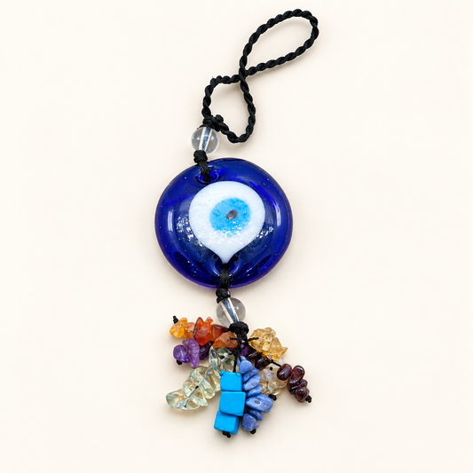 Blue Turkish eye hanger on a black cord with clear round beads and a multicoloured chip-bead tassel against an ivory background